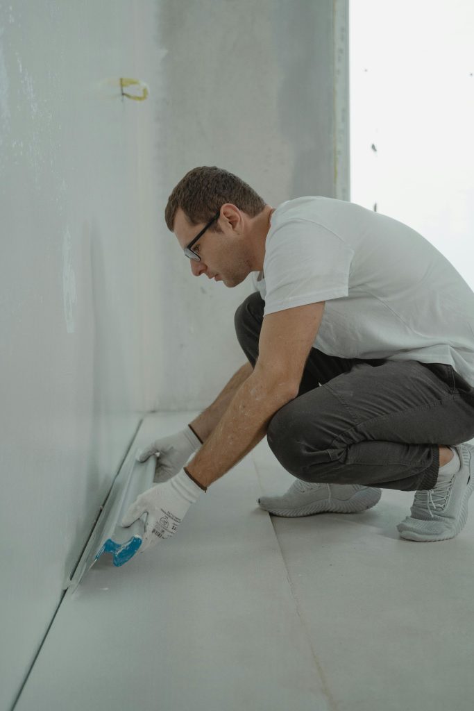 A man in shirt painting a house
